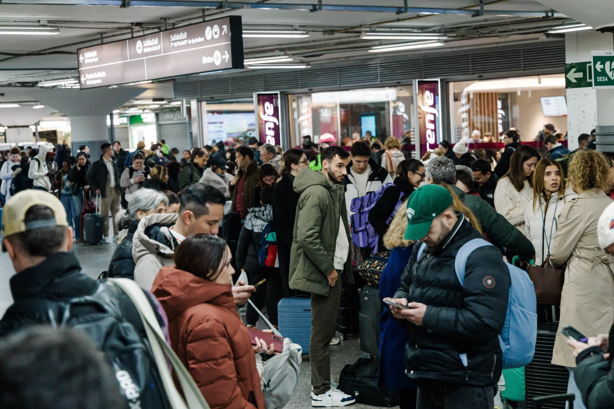 Passengers wait in the hall of Madrid train station on Sunday following the announcement of the suspension of service due to a train collision.