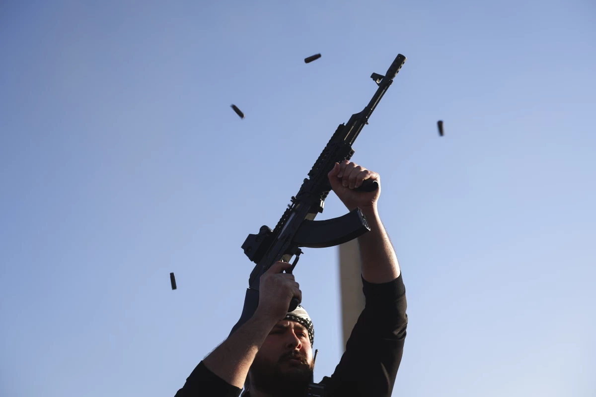 An opposition fighter fires his AK-47 in the air in celebration after opposition forces took control of the city in Damascus.