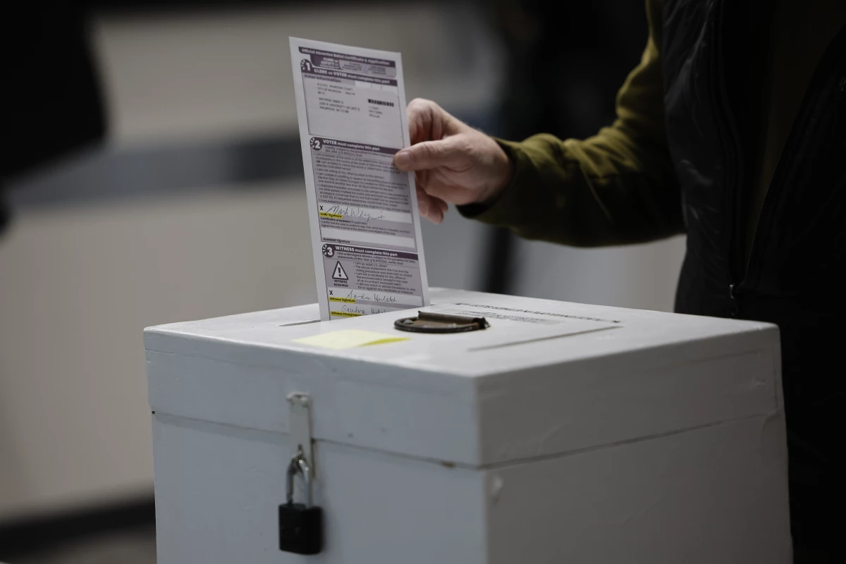 A man places his ballot in a box during early voting in Waukesha, Wis Tuesday, March 18, 2025.