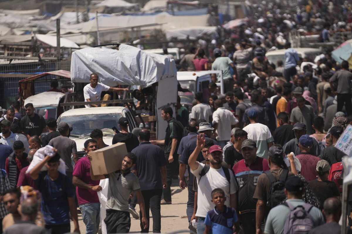 Palestinians carry bags containing food and humanitarian aid packages delivered by the Gaza Humanitarian Foundation, a U.S.-backed organization, in Rafah, southern Gaza Strip, Sunday, June 15, 2025.