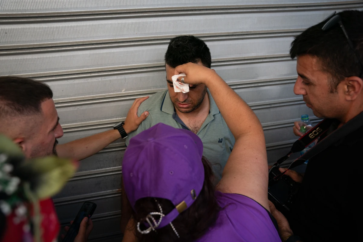 People help a Palestinian journalist who said he was injured by an Israeli police officer while documenting aggression against local shopkeepers on Jerusalem Day.