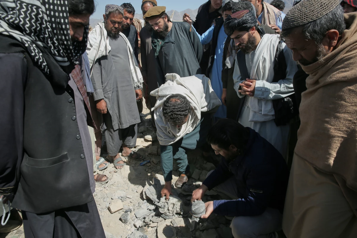 Residents and Taliban police gather the remains of a projectile at the site of a strike in Kabul, Afghanistan, on March 13.