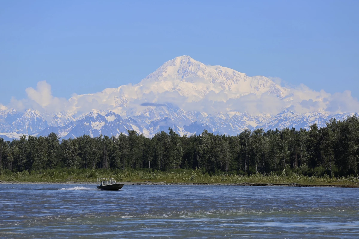 Denali, the tallest mountain on the North American continent, is seen here looming behind a boat on the Susitna River near Talkeetna, Alaska, in June 2021.