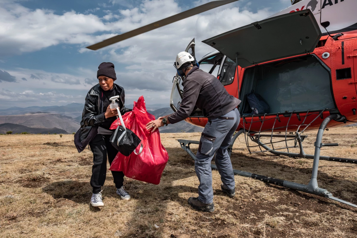 Dental therapist Senate Makhoali of the Lesotho Flying Doctor Service unloads her equipment from a Mercy Air helicopter after being dropped near the isolated village of Mophooko in the highlands of Lesotho. Makhoali had never before been in an aircraft before joining the project in May 2024.