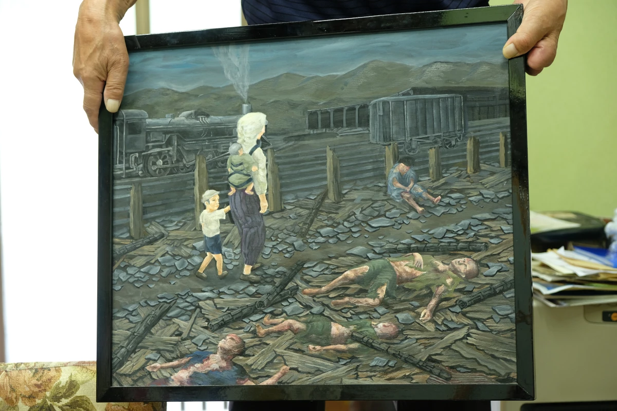 Toshiyuki Mimaki holds a painting based on his memory of entering the city of Hiroshima to look for his father the day after the US dropped an atomic bomb on the city. The painting shows 3-year-old Mimaki, walking while holding his mother's hand.