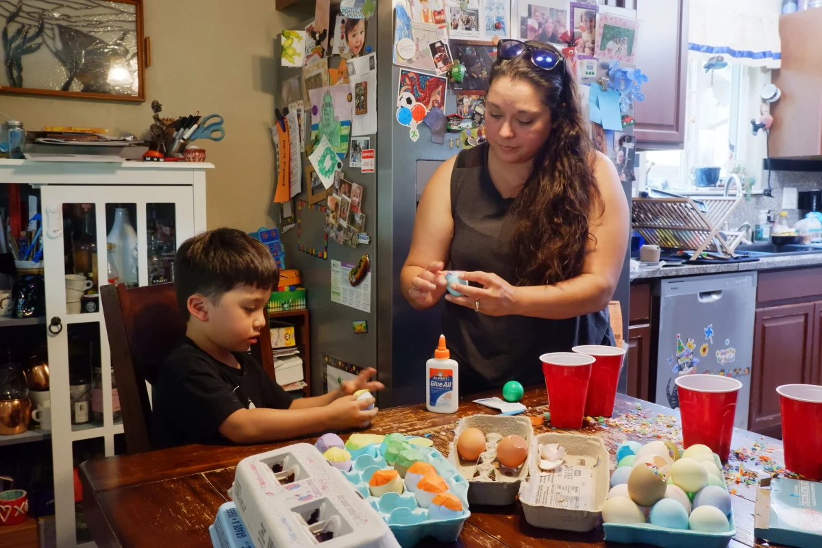 Denise Solis shows her four-year-old son Noah Solis how to seal a cascaron (confetti-filled egg) with tissue paper.