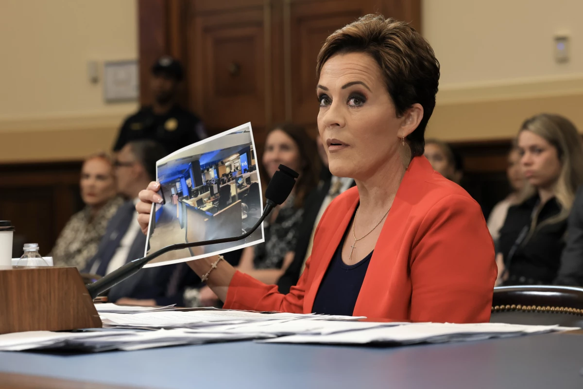 Trump adviser Kari Lake holds up a photograph, which she says shows an empty Voice of America (VOA) newsroom, as she speaks during a U.S. House Committee on Foreign Affairs hearing on June 25, 2025.