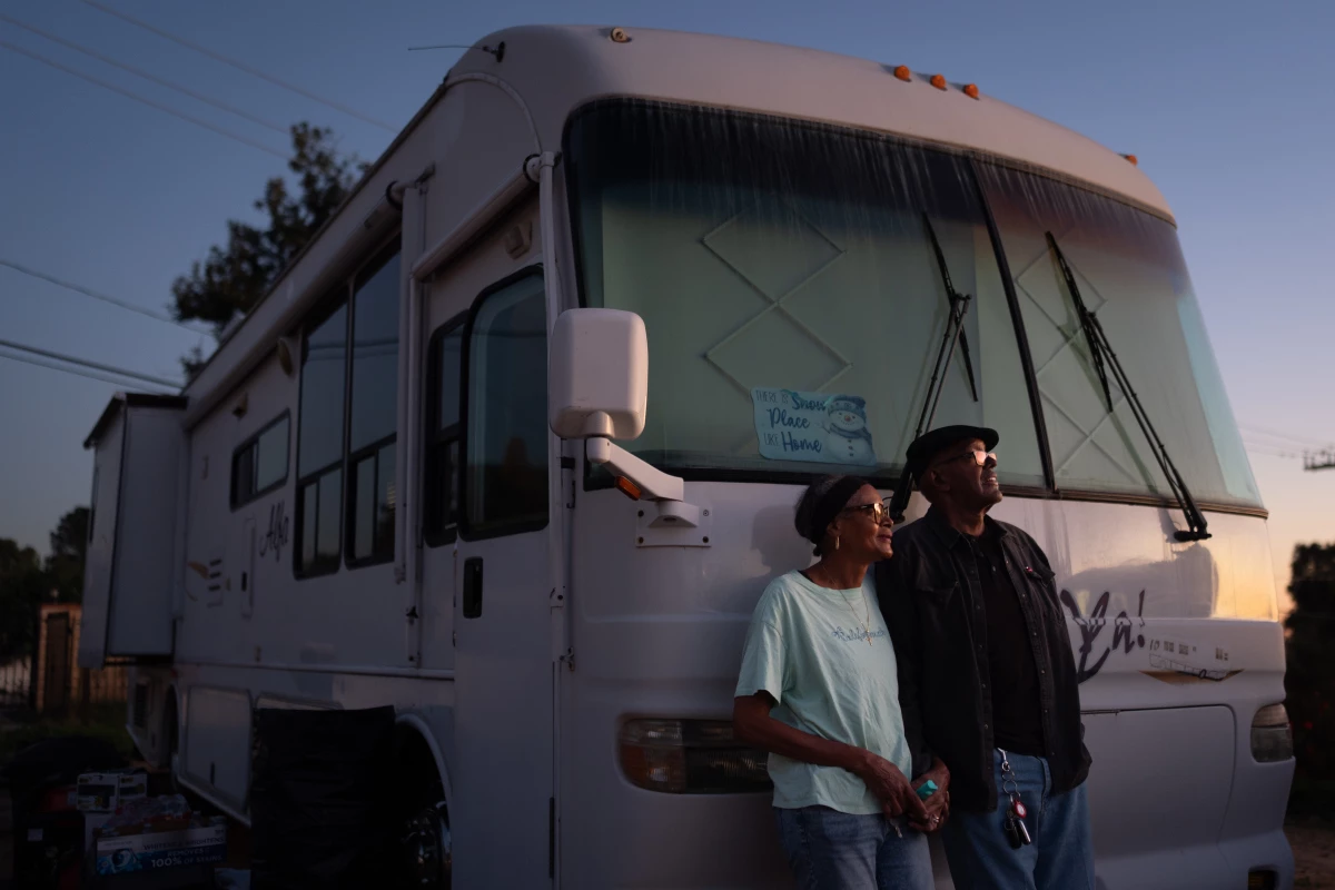 Ellaird Bailey and his wife, Charlotte, who lost their home in Altadena, Calif., to a wildfire in early 2025, stand in front of their recreational vehicle in December 2025. The RV is parked on the property where their house once stood. It can take years for disaster survivors to recover, often with the help of local Federal Emergency Management Agency workers.