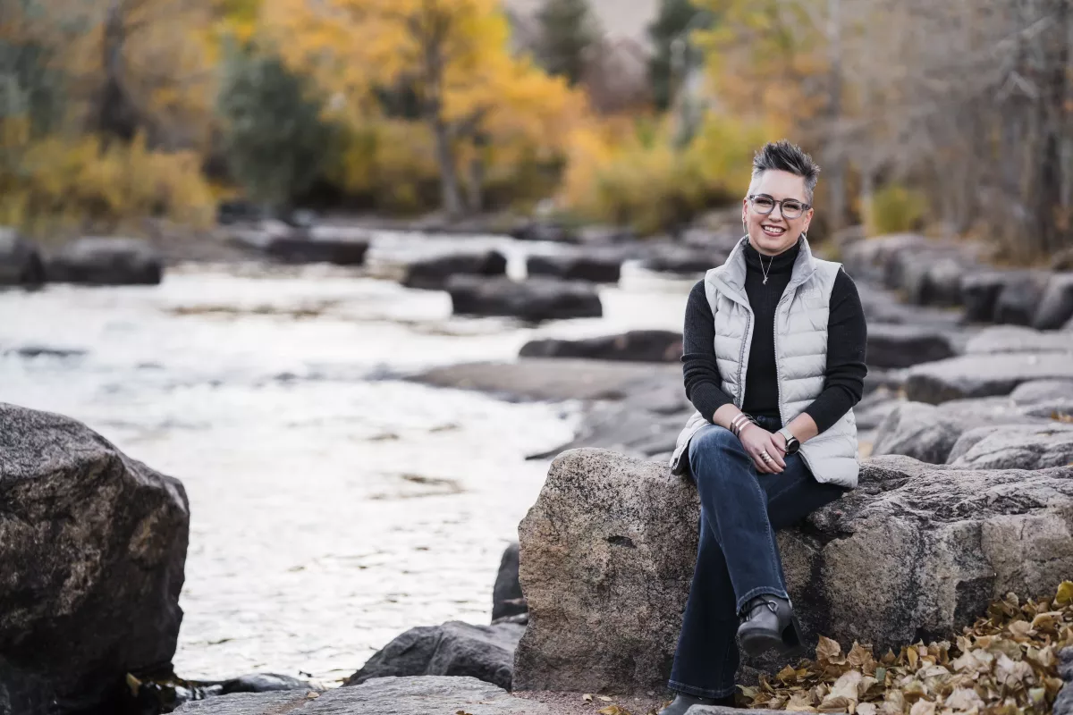 Britta Copt, a 26-year veteran of the EPA, sits on a rock at Clear Creek in Golden, Colo. She fears that former President Donald Trump will go after federal employee unions once again if he wins in November.