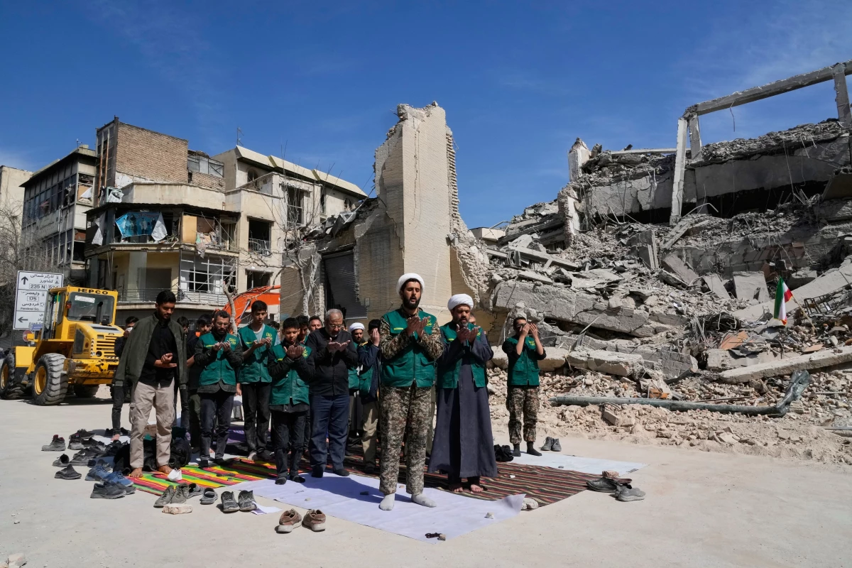 March 4: A cleric leads a group of volunteers in prayer next to a police facility struck during the U.S.–Israeli military campaign in Tehran, Iran.