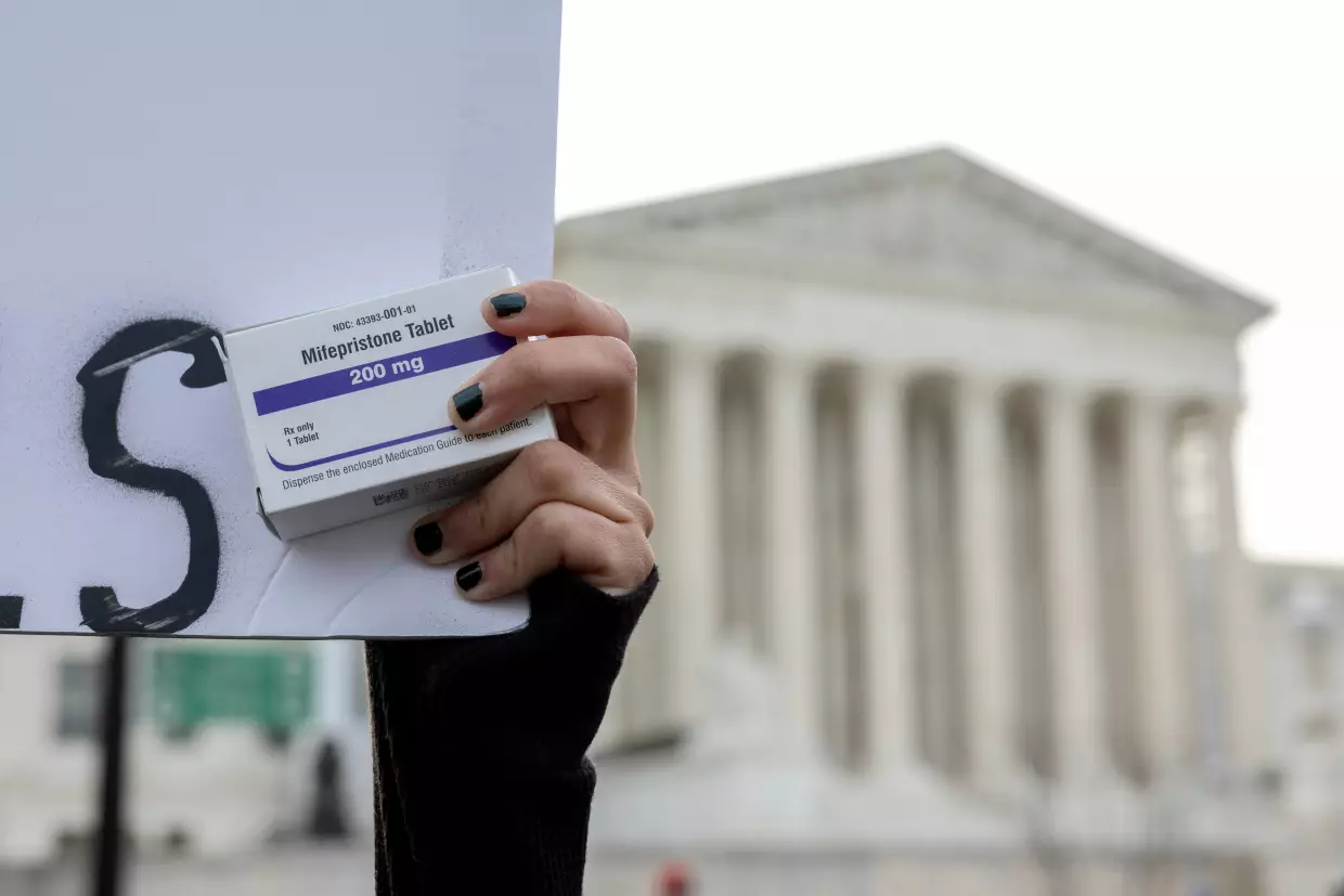 An abortion-rights activist holds a box of mifepristone pills as demonstrators from both anti-abortion and abortion-rights groups rally outside the Supreme Court on March 26, 2024.