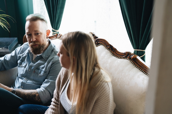 Ben Brewington looks at his wife, Sarah Brewington, while they sit on a couch in their living room.