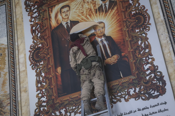 A Syrian opposition fighter tears up a painting Monday depicting Assad and his late father Hazef Assad at the airport in Aleppo, the country's second largest city.