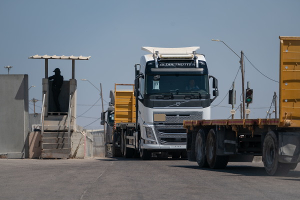 An Israeli border guard watches as trucks drive into Kerem Shalom border crossing in Israel, to load up with goods to be brought into Gaza.