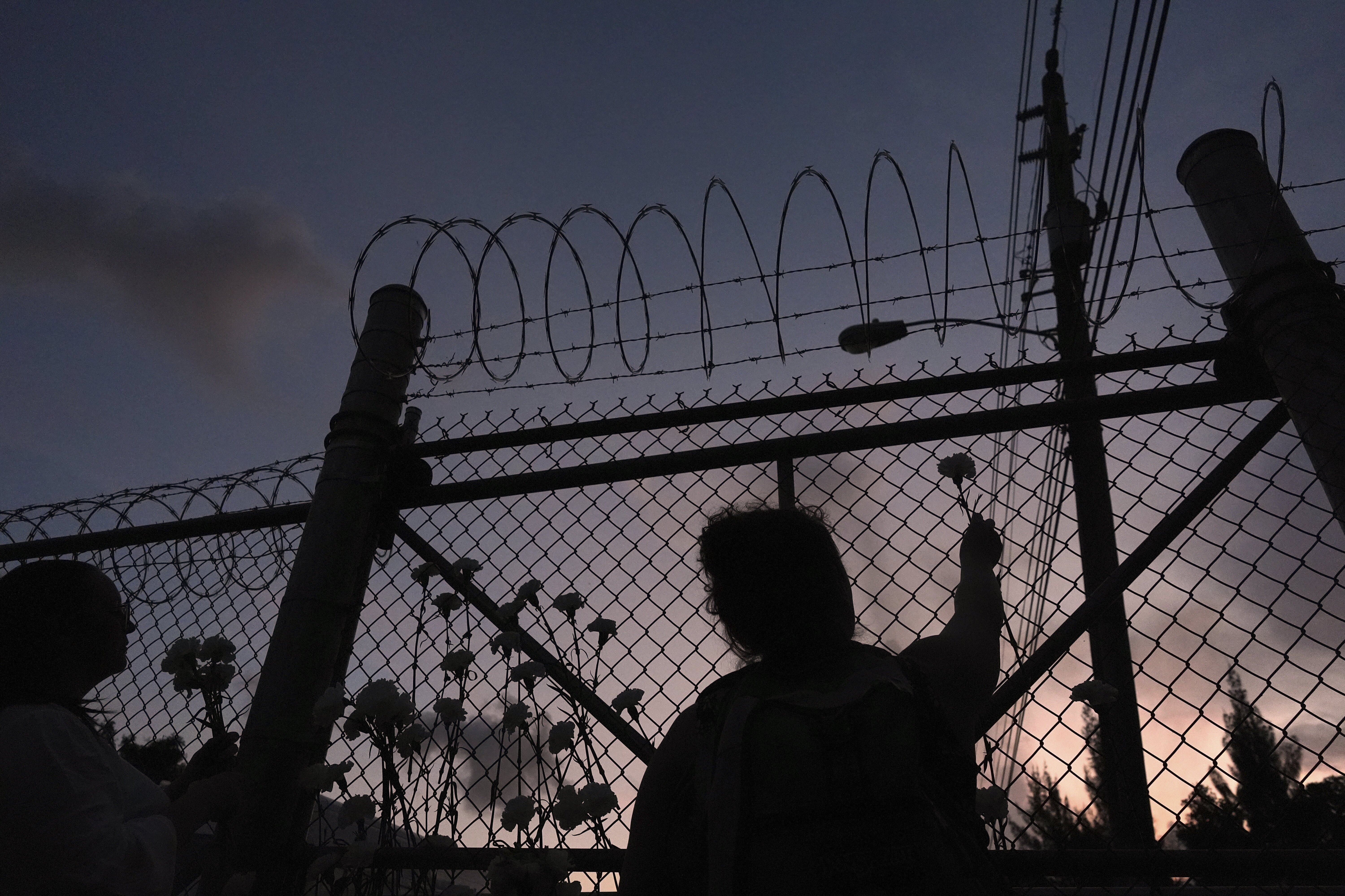 People place flowers on a fence outside Krome Detention Center in Miami in May 2025, during a vigil to recognize people who have died in U.S. Immigration and Customs Enforcement custody as well as those affected by mass deportations. (AP)