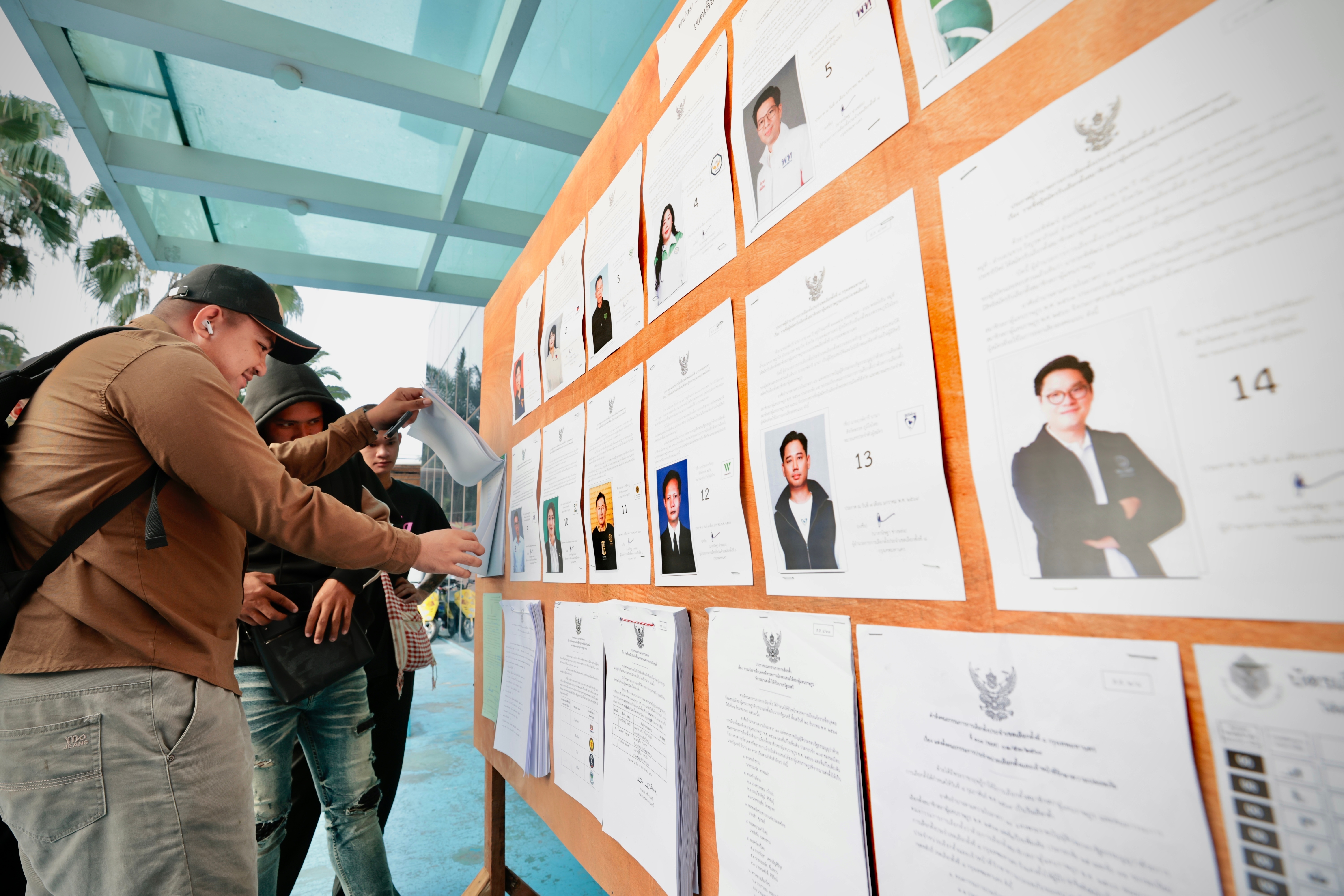 Voters look at candidates listed on a display board before entering a voting station for the general election in Bangkok, on Sunday, Feb. 8, 2026.