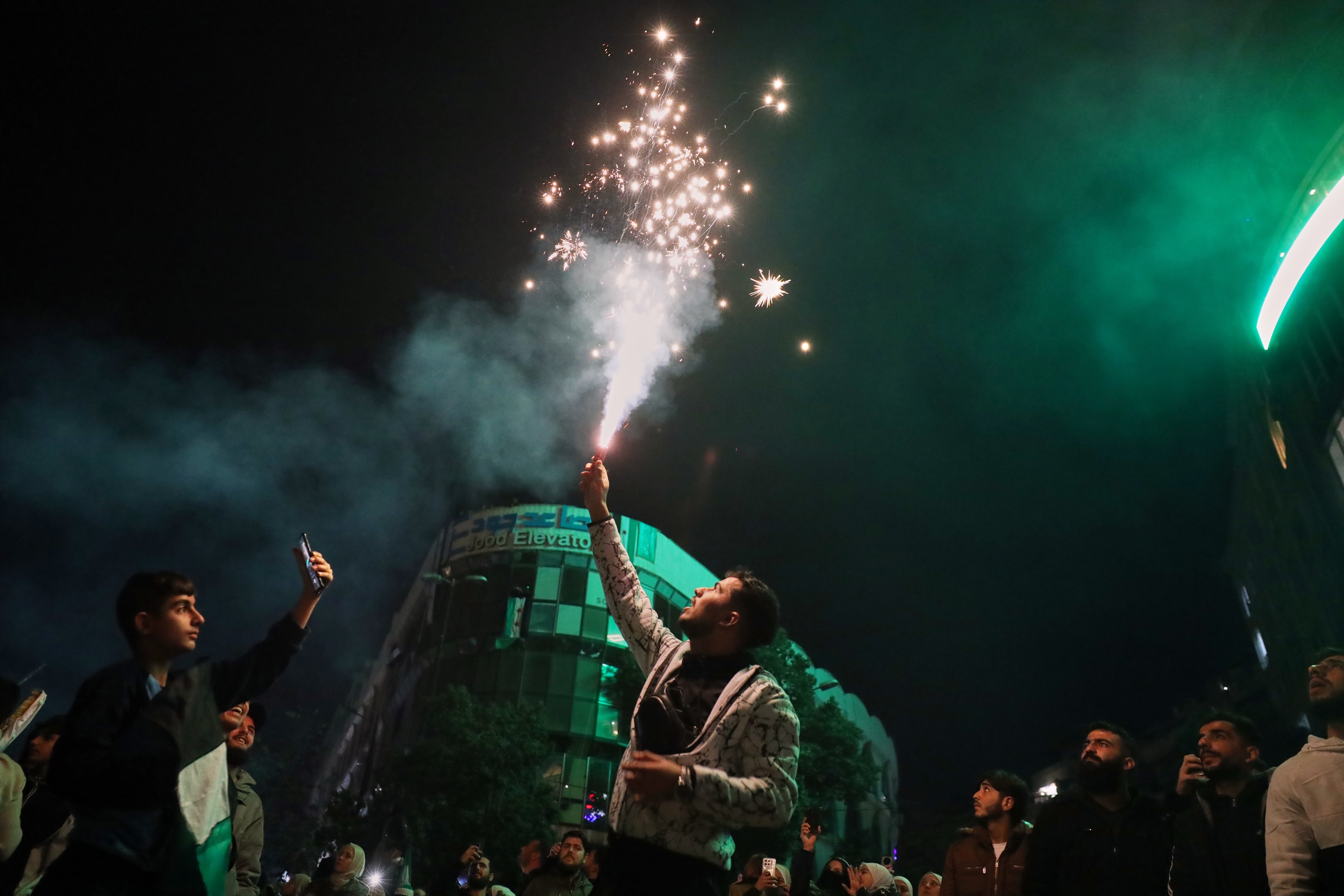 A man lights a flare during celebrations marking the first anniversary of the ousting of the Bashar al-Assad regime in Clock Square, Homs, western Syria, Monday.