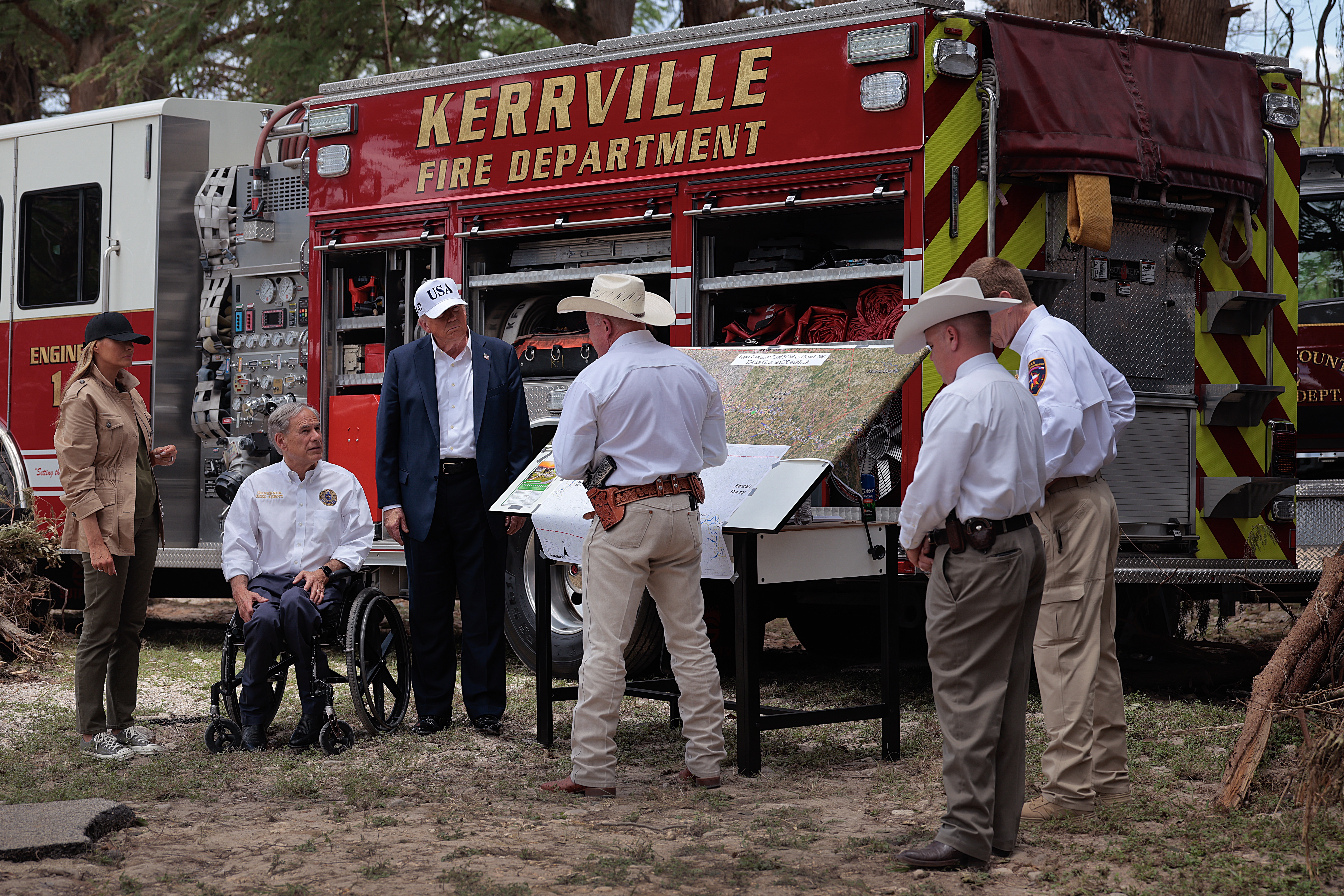 President Trump, first lady Melania Trump and Texas Governor Greg Abbott meet with local emergency services personnel as they survey flood damage along the Guadalupe River on July 11, in Kerrville, Texas.