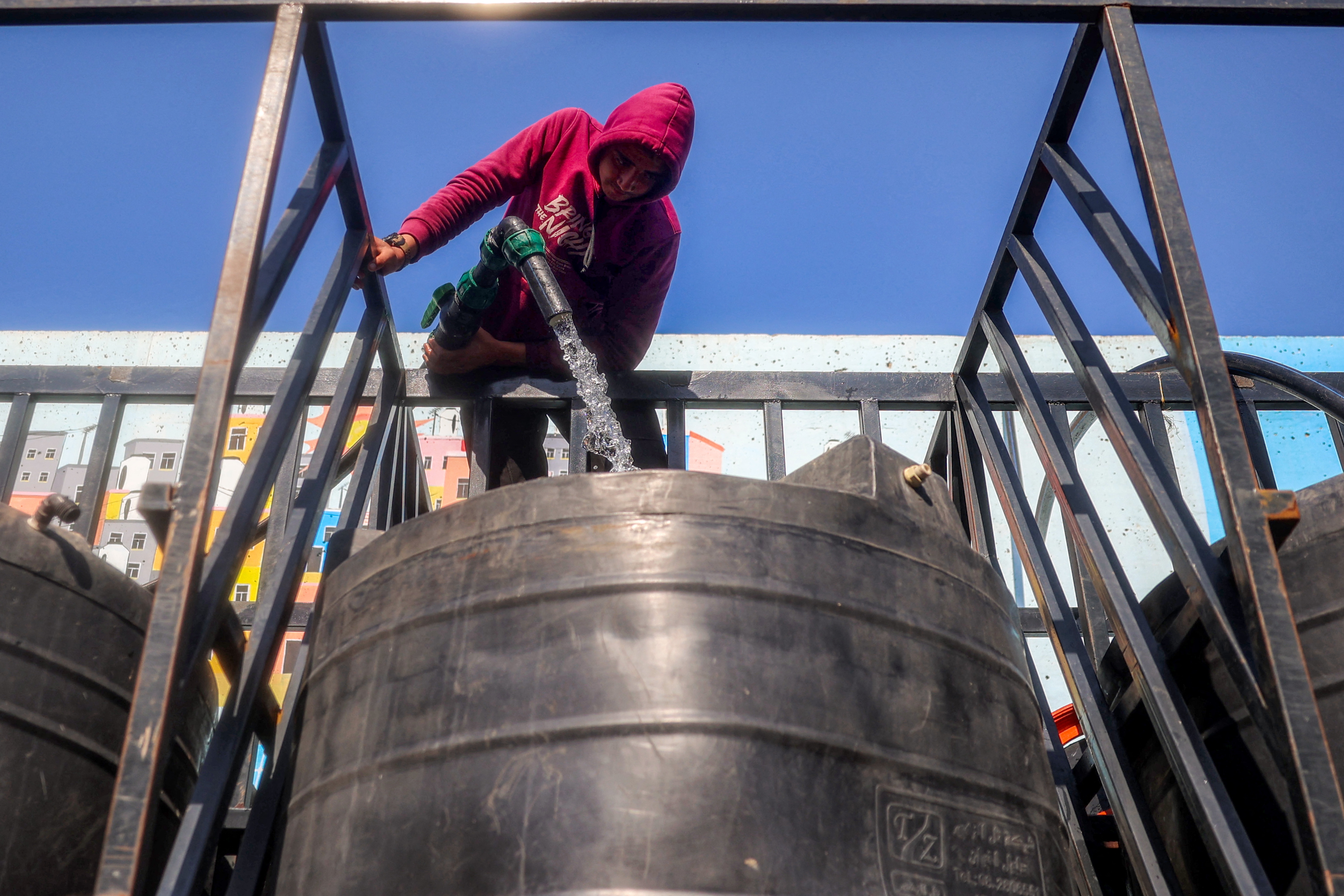 A man fills up a cistern on the back of a truck with water at the Southern Gaza Desalination plant, which stopped working earlier after Israel cut off electricity supply to the Gaza Strip on Sunday. The plant will have to work on generators now in an area where fuel is in very short supply.