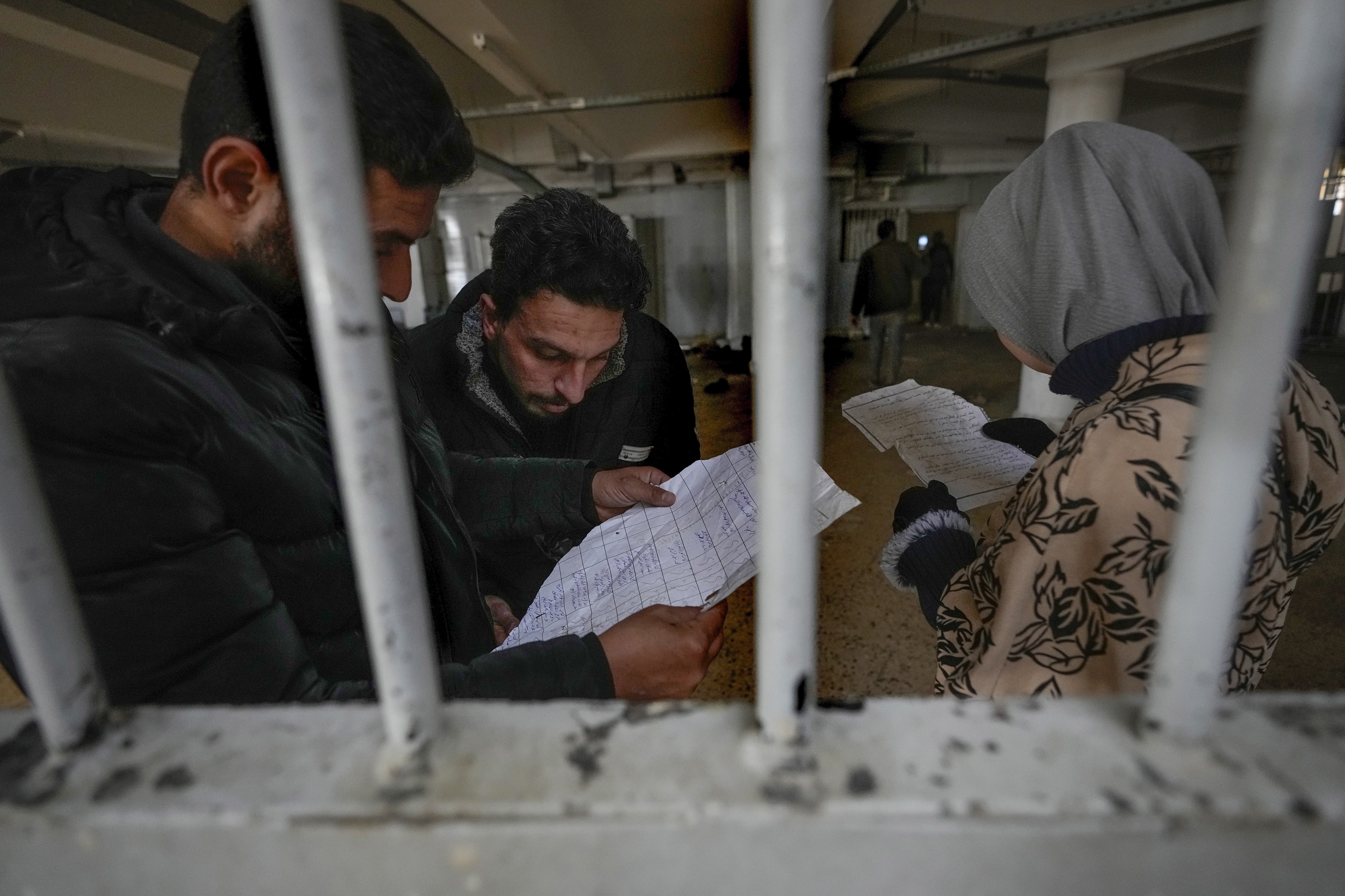 Syrians inspect documents in the infamous Saydnaya prison, just north of Damascus, on Monday. Crowds are entering the prison, known as the "human slaughterhouse," following the ouster of Bashar al-Assad and the release of thousands of prisoners who were held by the regime.