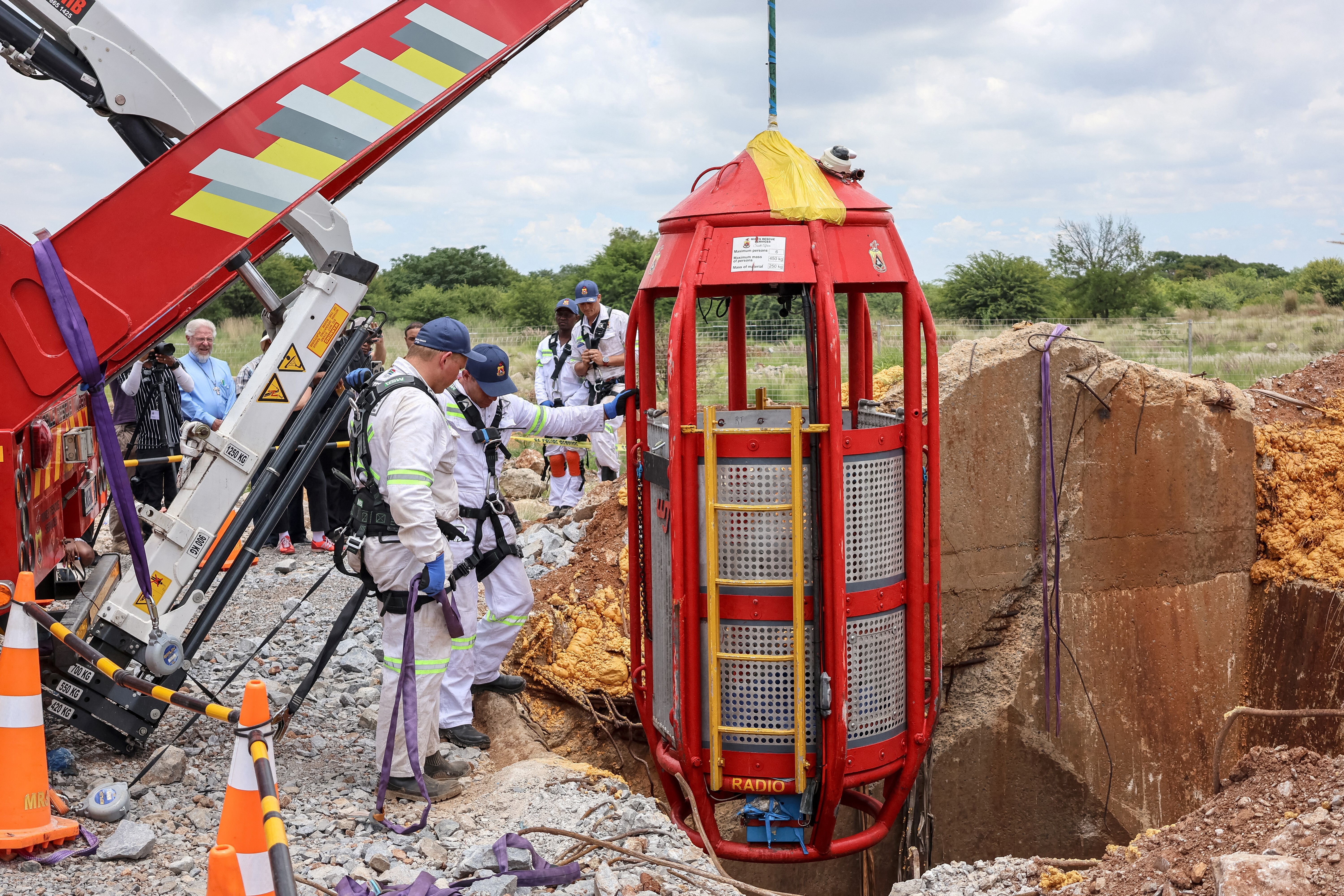Rescue workers look on as a cage is lifted from an abandoned gold shaft in Stilfontein on January 16, 2025.