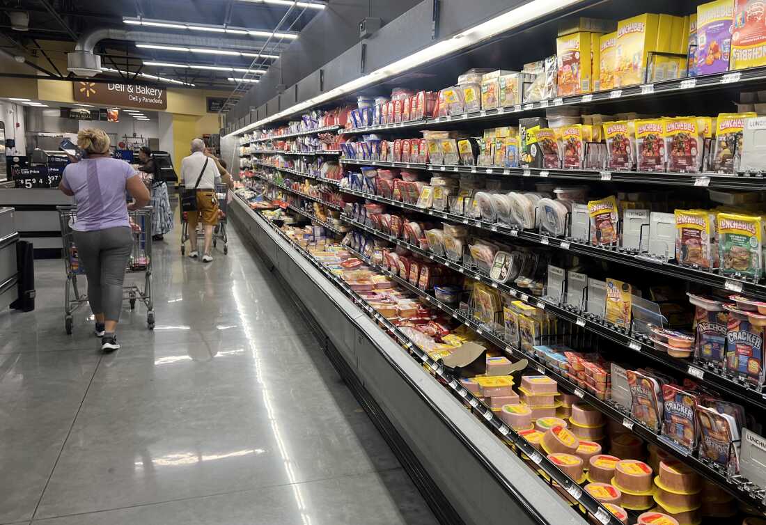 Customers shop in the deli meat aisle of a grocery store in Miami in October.
