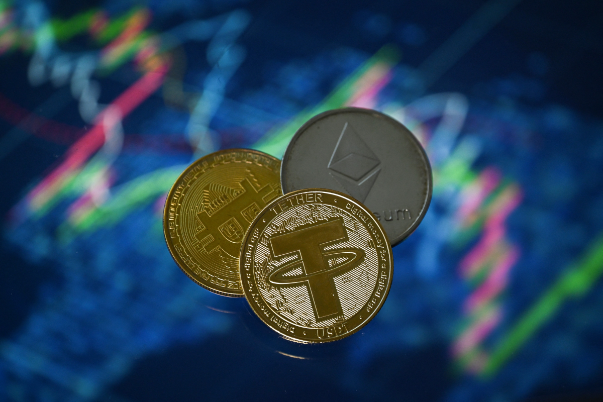 An illustration picture shows a gold-plated souvenir Tether stablecoin, along with representations of crypto currencies Bitcoin and Ethereum coins.