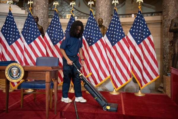 A worker vacuums the stage in Statuary Hall, in the Capitol, where President Trump was scheduled to sign a bipartisan housing bill on Wednesday before he abruptly cancelled the signing.