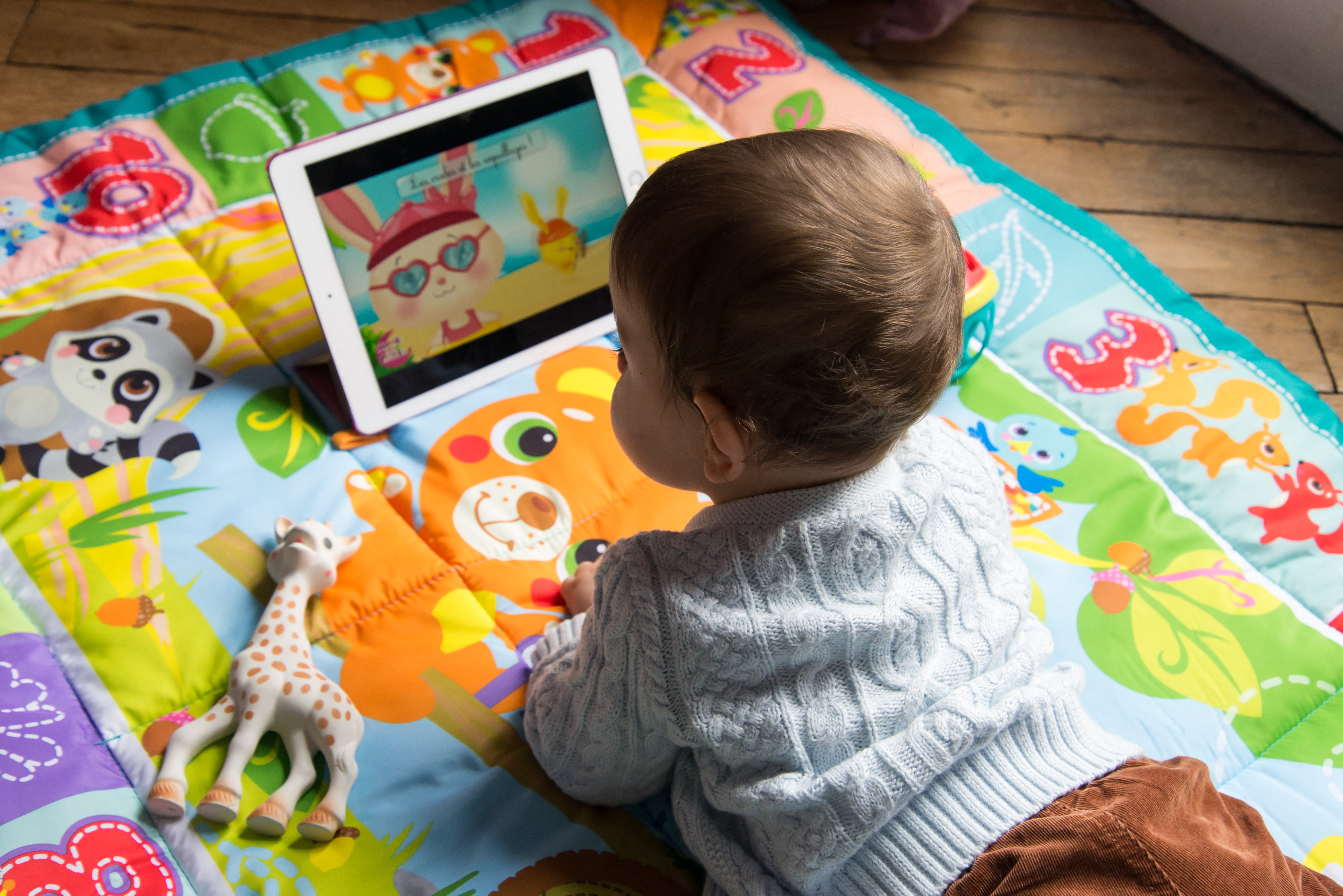 An 8-month-old baby watches a cartoon on a tablet. A survey by Common Sense Media found that 80% of parents are worried about their children spending too much time on screens.