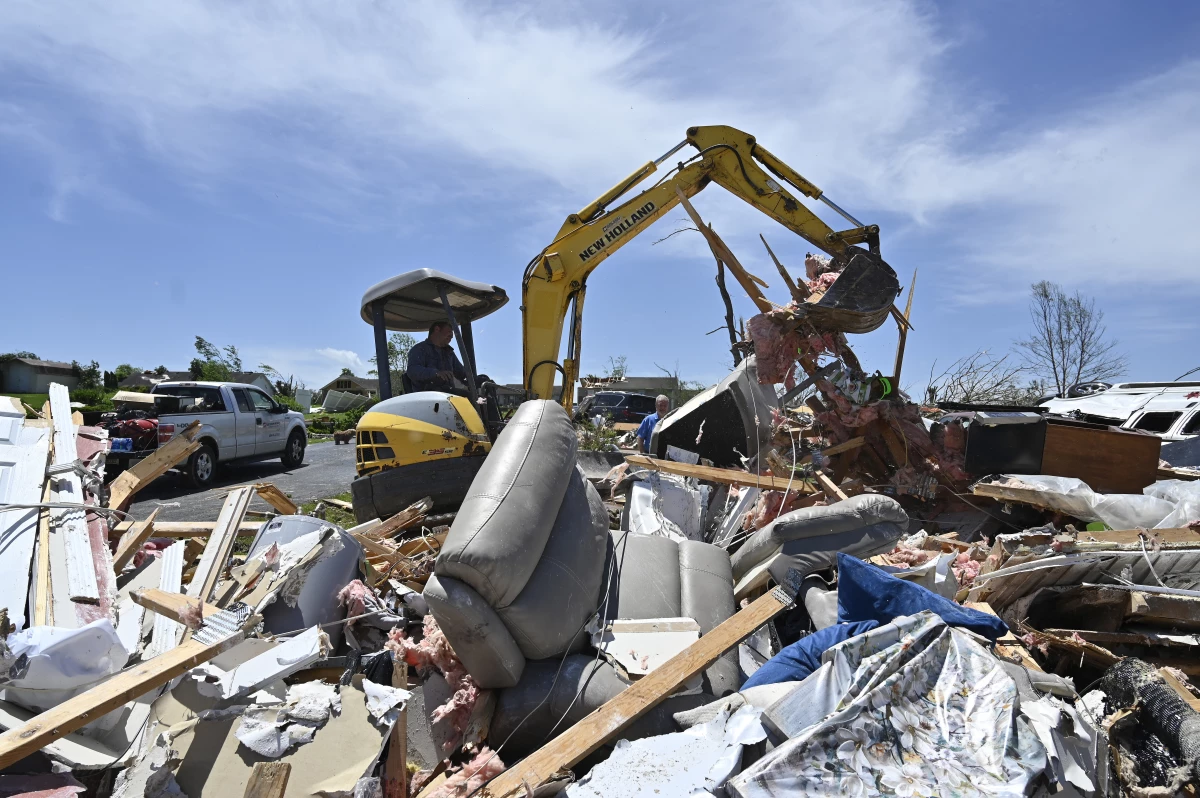 A man uses a back hoe to move debris into a pile following severe storms in London, Ky., on Saturday.