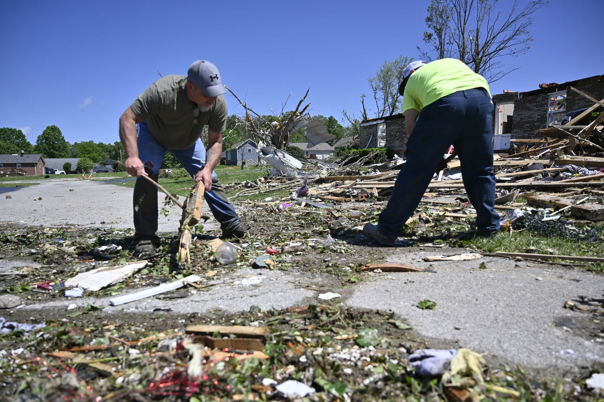 Volunteers help clear debris from a road following severe storms last night in London, Ky., on Saturday.