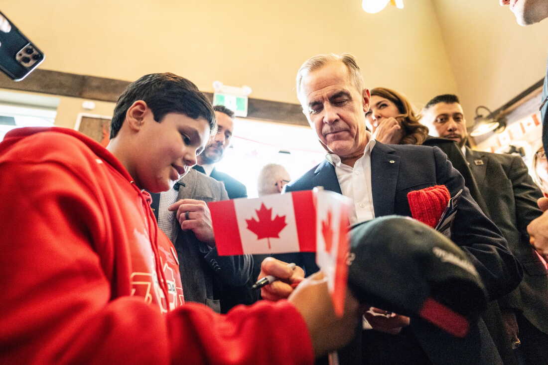 Canada's Prime Minister Mark Carney signs an autograph as he attends a national unity rally in Red Deer, Alberta, Friday Oct. 16, 2026.