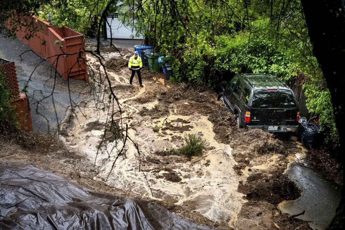 Permit Sonoma Director Tennis Wick crosses a mudslide to inspect a home as heavy rains fall near Healdsburg in unincorporated Sonoma County, Calif., on Friday.