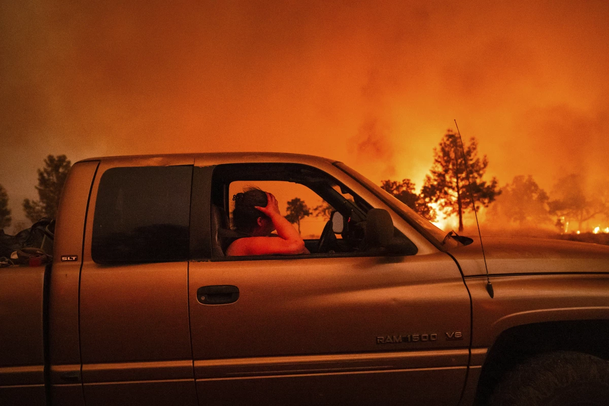 Andrea Douglas holds her head while evacuating as the Park Fire jumps Highway 36 near Paynes Creek in Tehama County, Calif., on Friday.