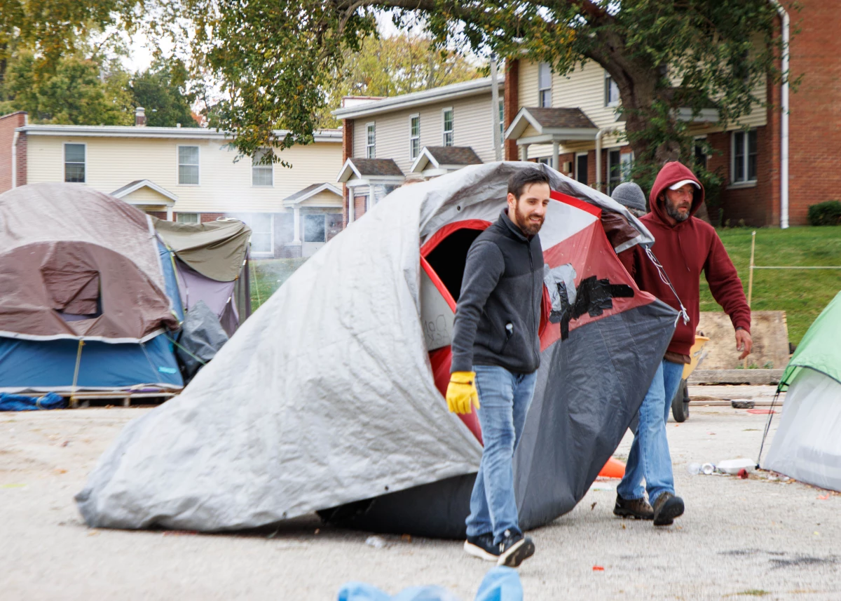 A Home Sweet Home Ministries' employee and a volunteer drag a tent to a dumpster in a church parking lot that was being used as a homeless encampment.