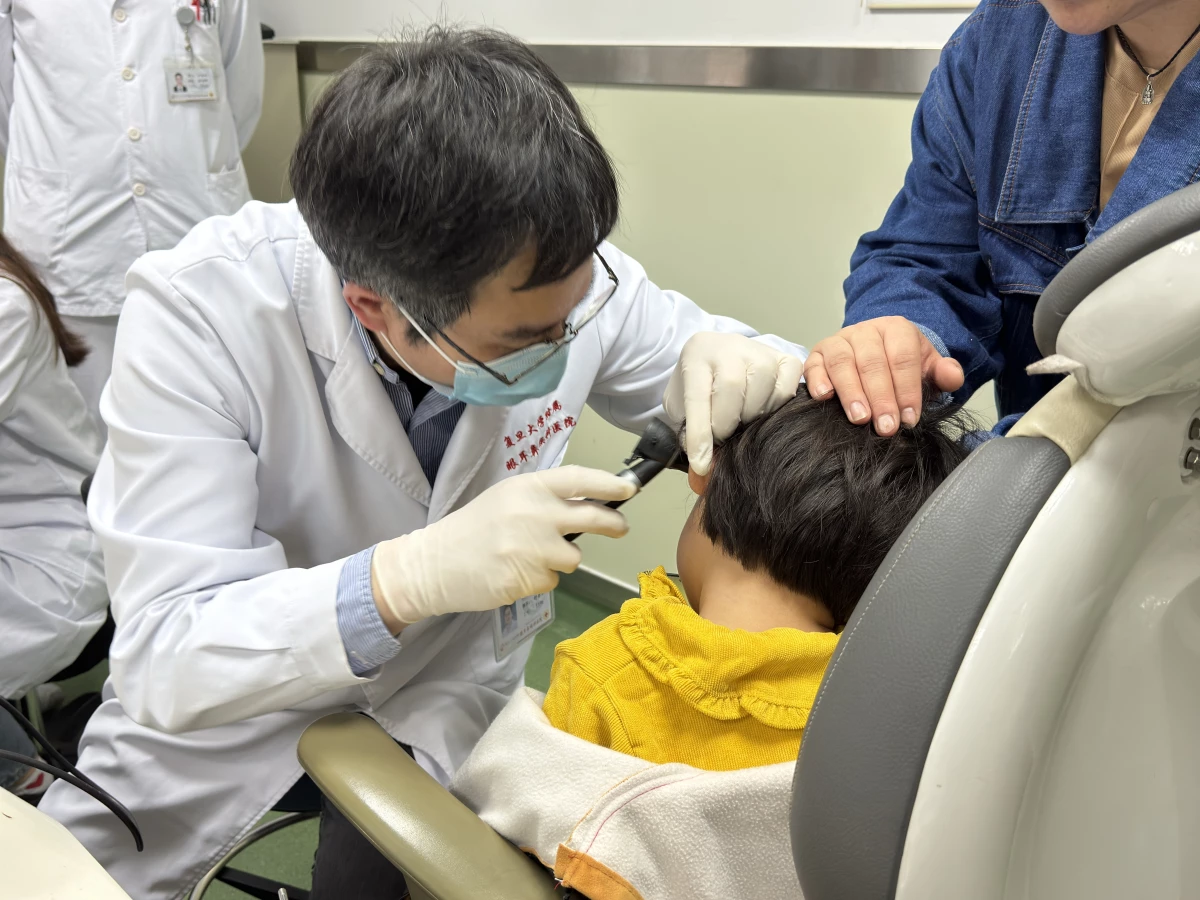 Dr. Yilai Shu examines a young patient at the Eye & ENT Hospital of Fudan University in China.