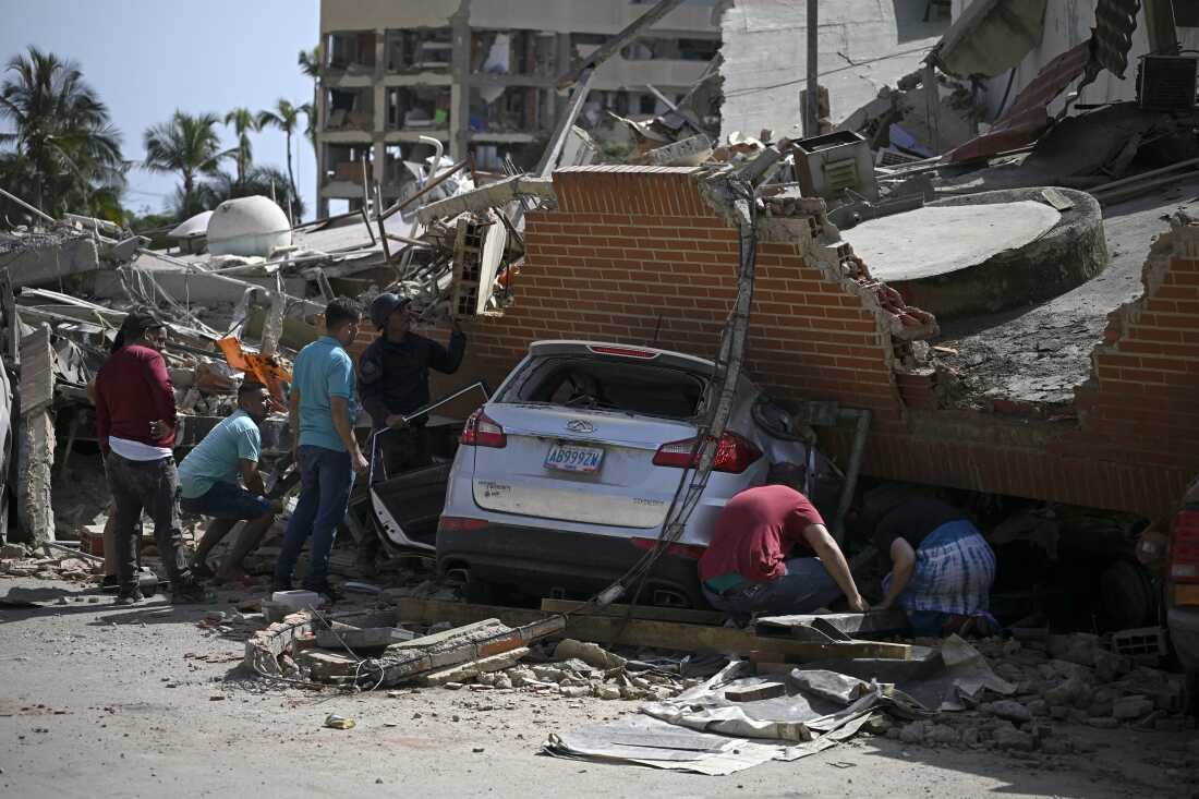 People search through the rubble around a car trapped beneath the collapsed remains of a residential building following an earthquake in Catia La Mar, La Guaira state, about 30 km northwest of Caracas.