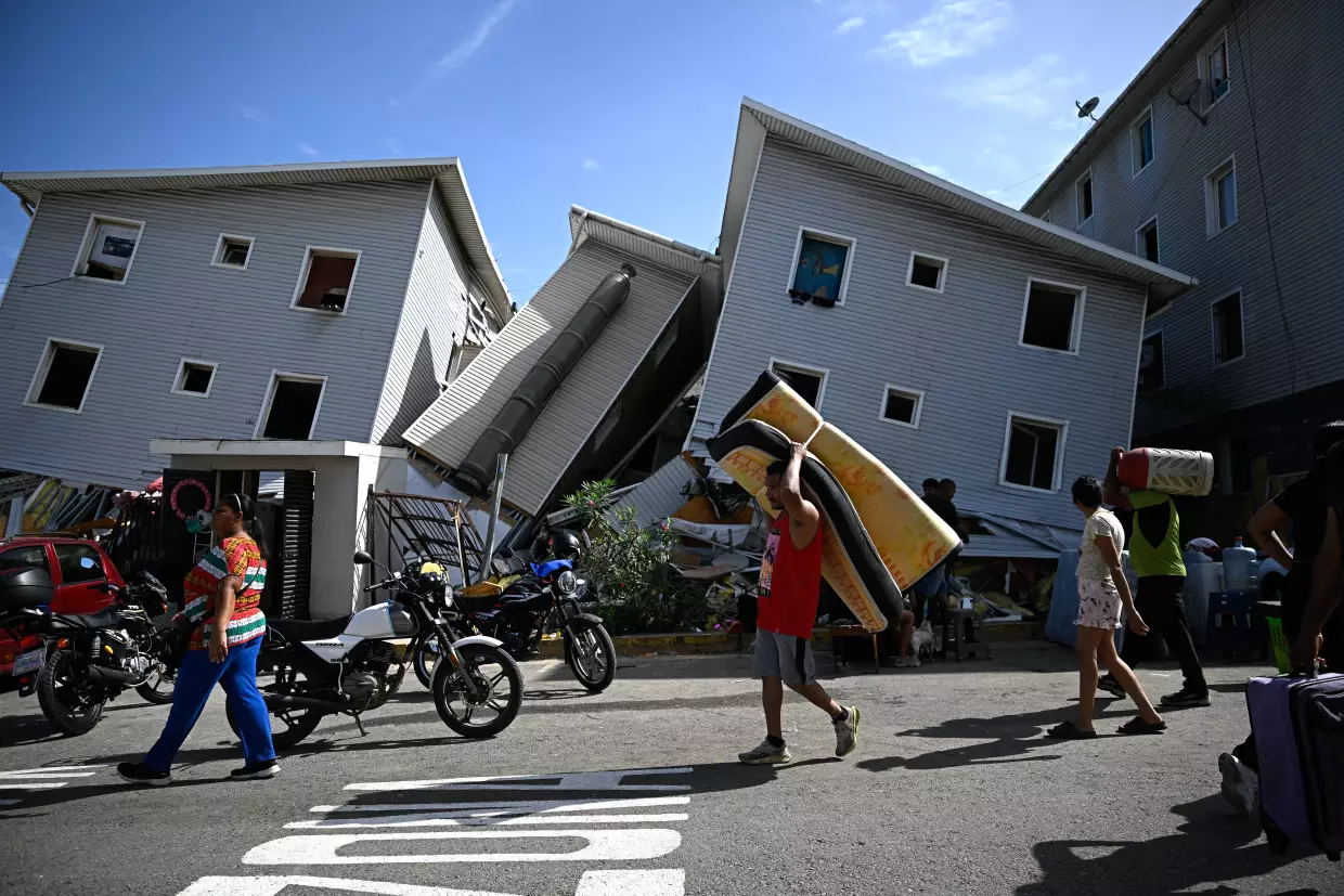 A man carries a mattress past damaged residential buildings in Catia La Mar, about 18 miles northwest of Caracas. Twin earthquakes on June 25 have killed at least 164 people and destroyed multiple buildings near the capital. The U.S. has pledge a substantial amount of aid to address the aftermath of the disaster.