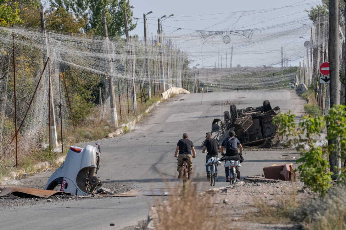 Ukrainian troops ride bikes under an anti-drone net in the frontline town of Druzhkivka, Ukraine, on Sept. 12. Both the Russian and Ukrainian forces have put up nets to guard against drones. The troops often move on foot or on bikes because tanks, armored personnel carriers and other military vehicles are easily spotted and often attacked.