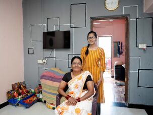 Savitha Yadava and her daughter, Poonam, 19, pose in their living room of their new apartment. There's a small shrine in one corner. Decorating her home has become a passion, she says.