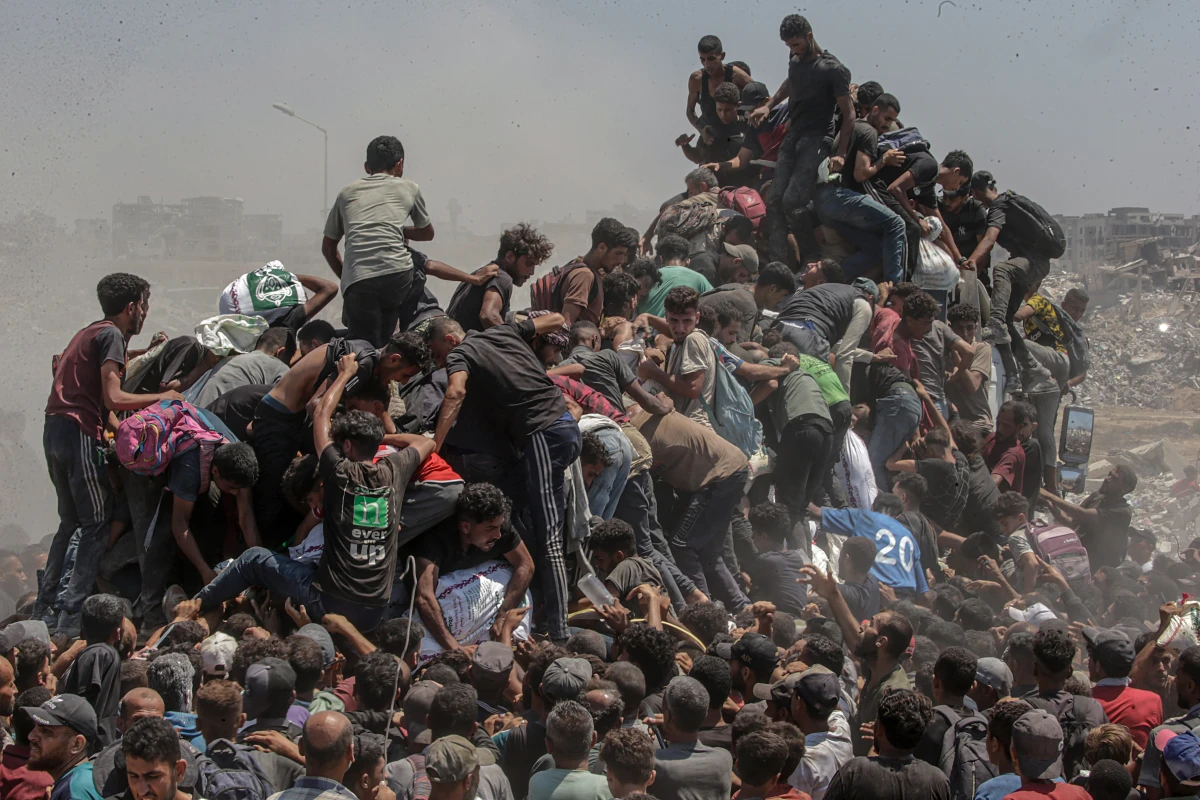 Palestinians climb onto an aid truck as it enters the Gaza Strip via the Zikim Crossing. They're hoping to obtain flour during what the Israeli military called a 'tactical suspension' in operations to allow humanitarian aid through. Gaza. July 27, 2025.