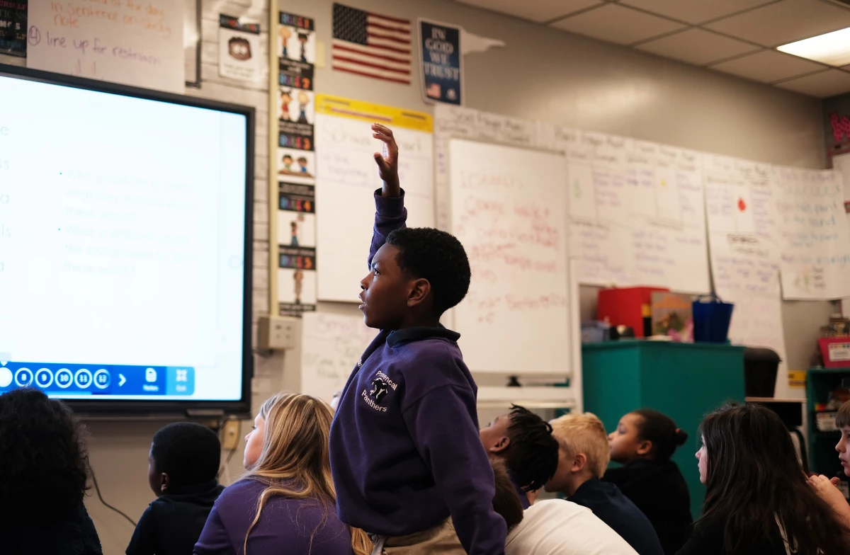 Second grader Ethan Williams raises his hand during whole-group reading instruction.