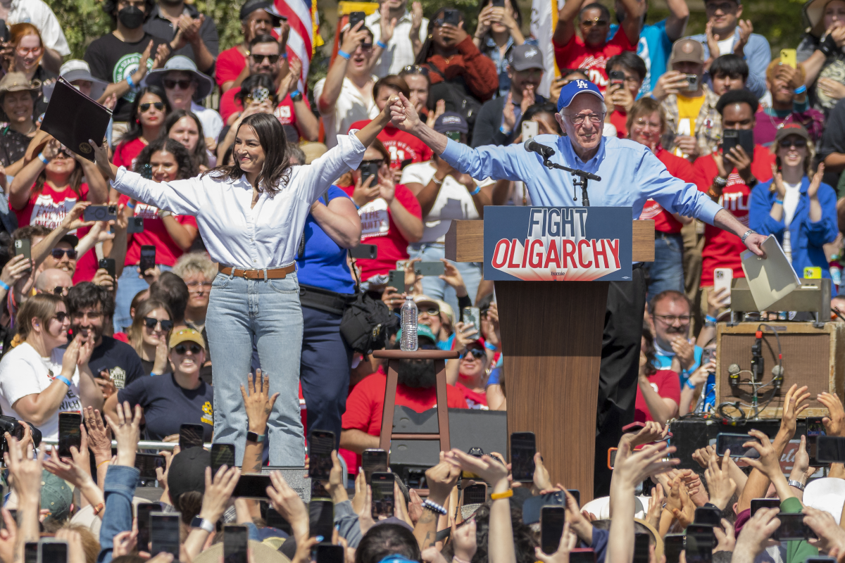 U.S. Sen. Bernie Sanders (I-Vt) And Rep. Alexandria Ocasio-Cortez (D-Ny) Hold Hands During A Stop On Their 'Fighting Oligarchy' Tour At Grand Park On April 12, 2025 In Los Angeles, California. An Estimated 36,000 People Attended The Rally Which Also Saw Neil Young And Joan Baez Perform.