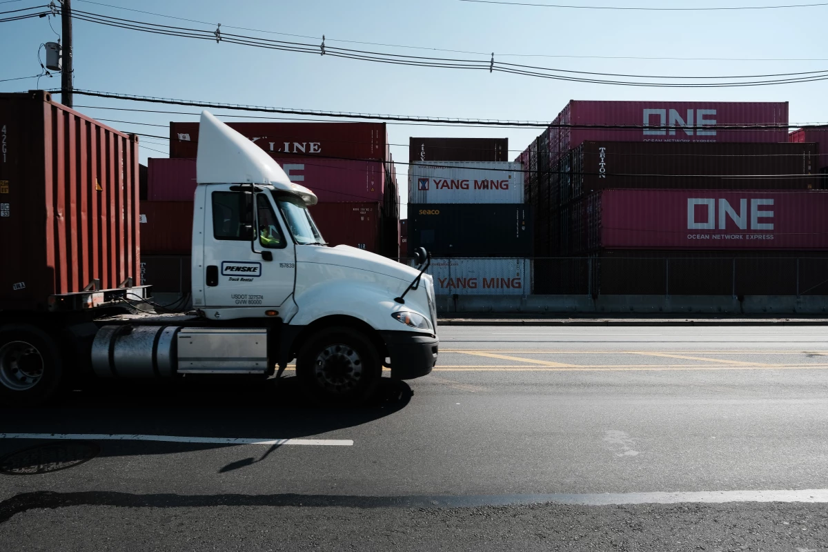 Trucks move past cargo containers at a port in Bayonne, N.J., in 2021. The state is adopting California's Advanced Clean Trucks rules, which require at least 7% of medium- and heavy-duty vehicles sold in the state to be zero-emission for model year 2025. Dealers are petitioning for a delay, so far unsuccessfully.