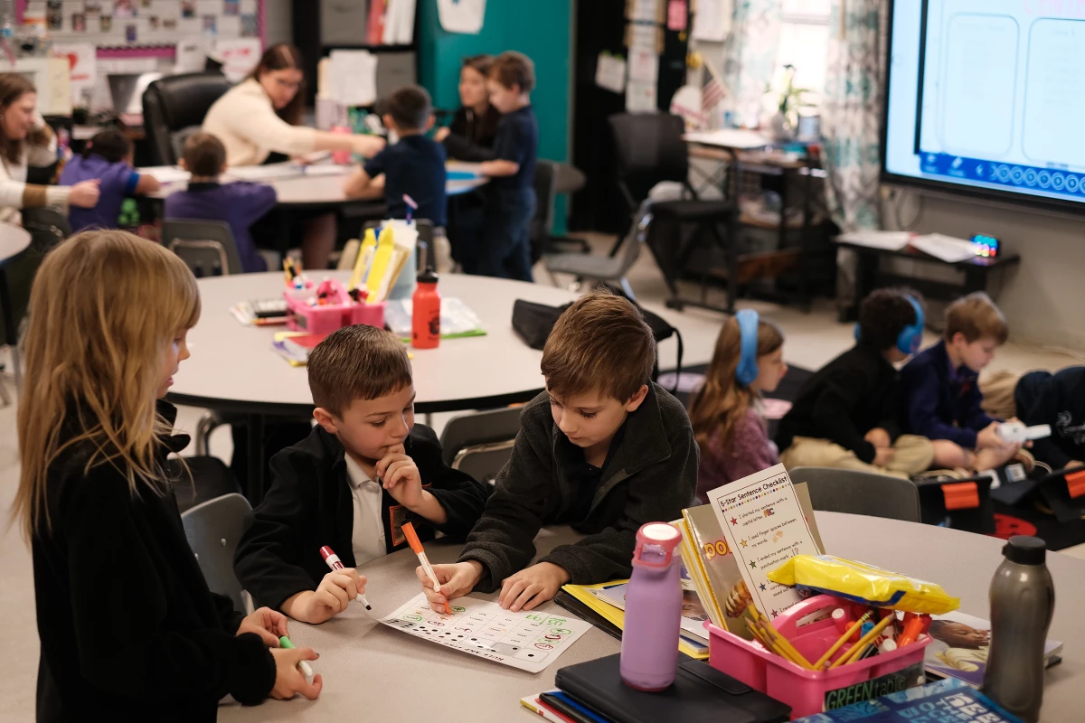 Second graders Serena Lacour, Luke Busby and Dylan Poche work on a word-identification reading game, while other groups work with their teacher, Cady Caskey, on sounding out words.