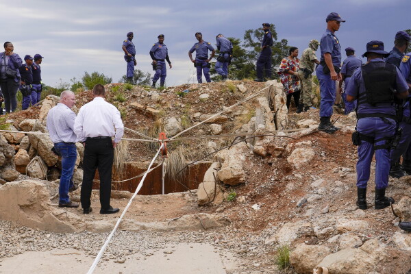 Police officers and private security personnel stand by the opening of a reformed gold mineshaft where illegal miners are trapped in Stilfontein, South Africa, Nov. 15.