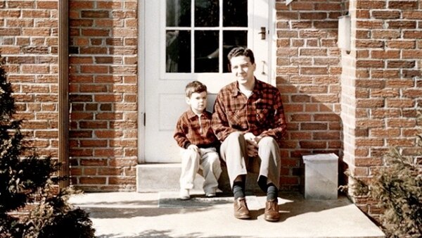 Future NPR critic Bob Mondello and his father, Tony Mondello. They sit on a step in front of the door of a brick home.