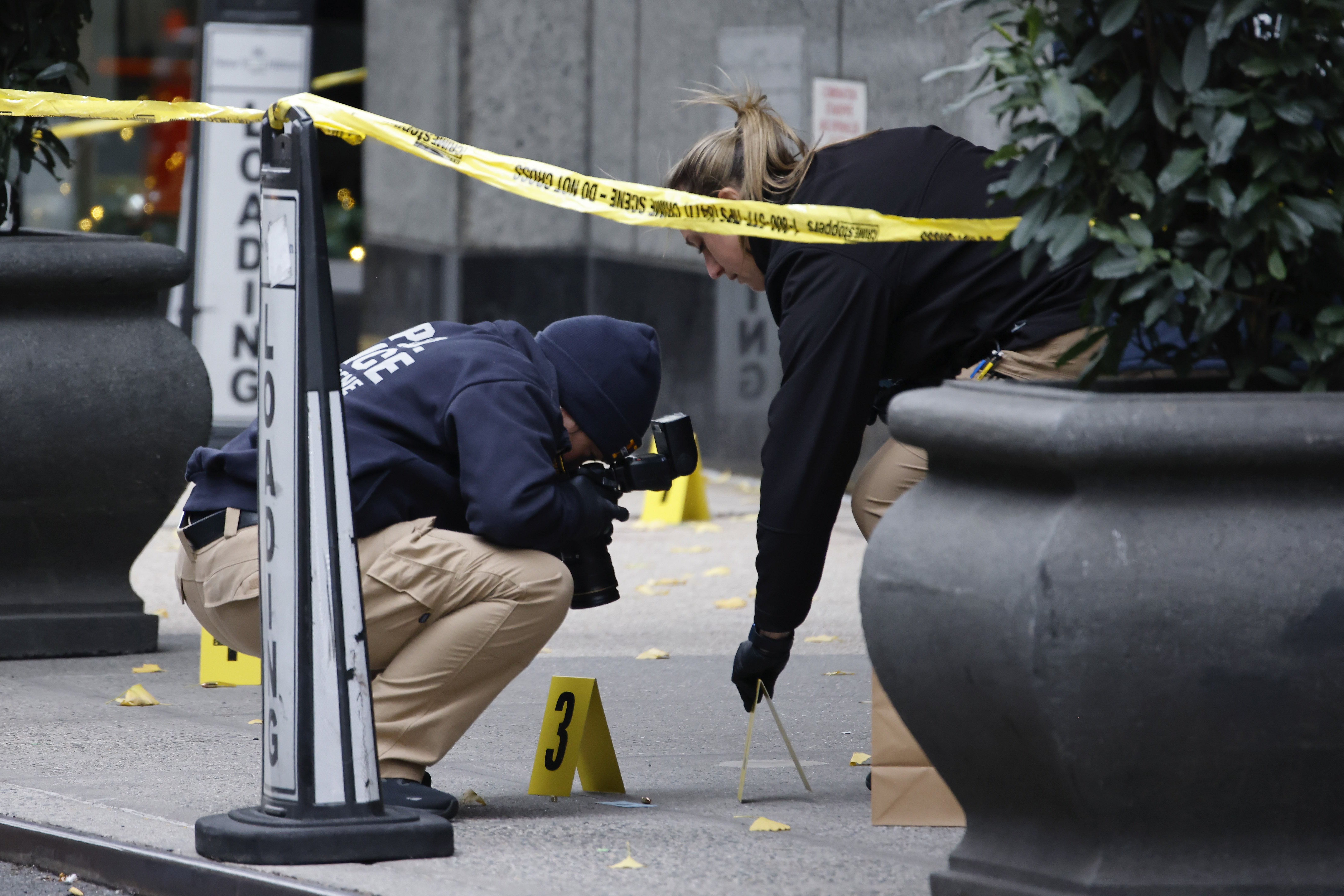 Members of the New York police crime scene unit photograph bullets lying on the sidewalk as they investigate the scene outside the Hilton Hotel in midtown Manhattan where Brian Thompson was fatally shot on Wednesday. (AP)