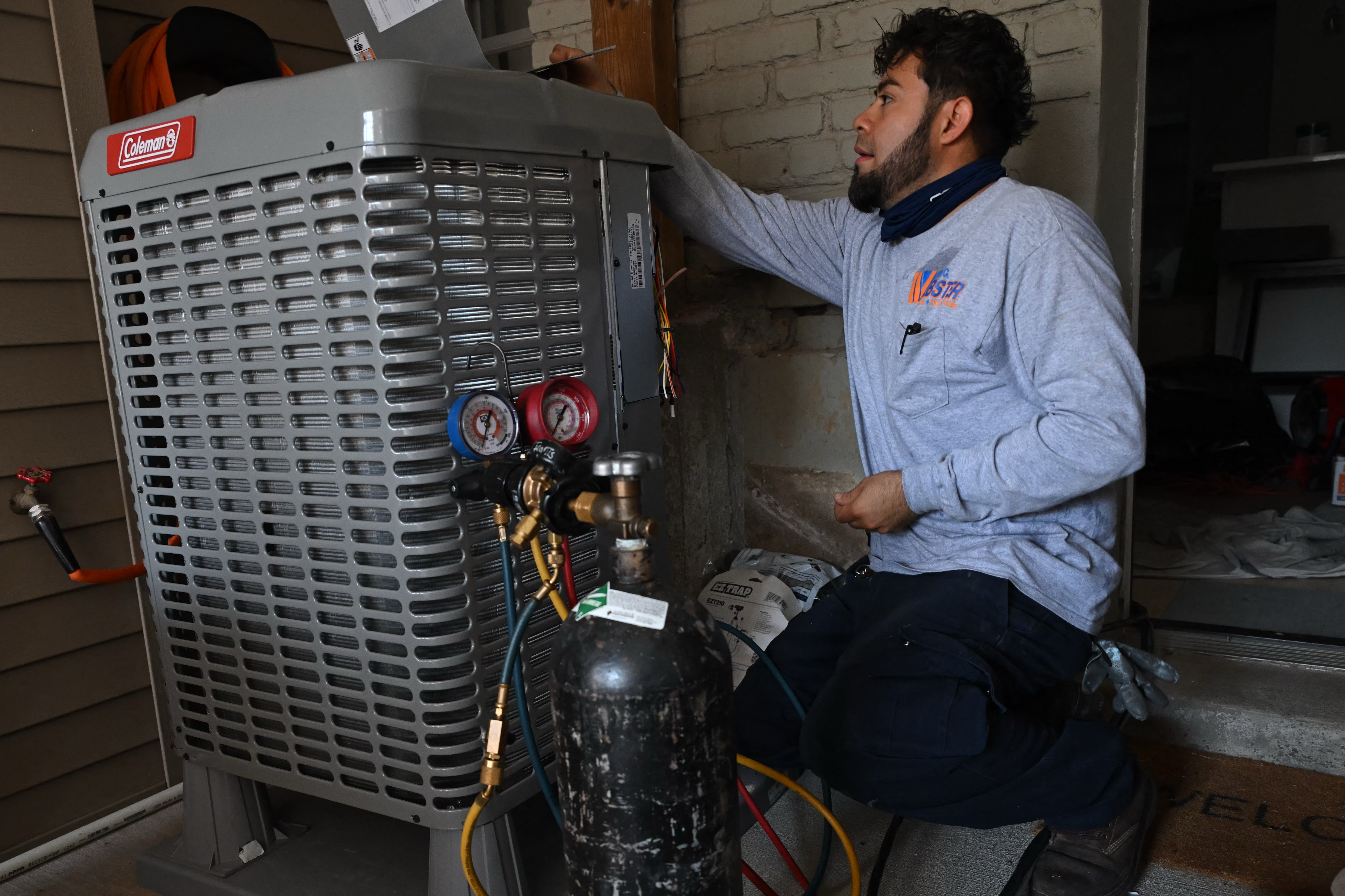 A technician installs an electrical heat pump at a home in Washington, DC, in August 2024.