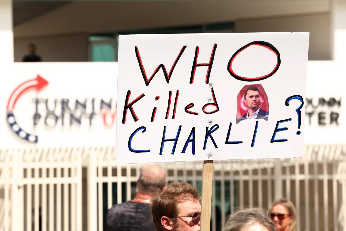 A person carries a sign that reads 'Who killed Charlie' at a makeshift memorial for right-wing activist and Turning Point USA founder Charlie Kirk outside of their headquarters in Phoenix, Arizona. Social media has been fertile ground for speculation around what motivated the alleged killer, Tyler Robinson. It has also spread many conspiracy theories about the killing.